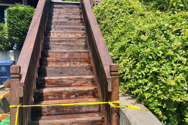 A wooden staircase marked with yellow tape, indicating caution or restricted access for safety purposes.