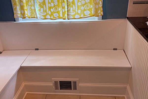 A white bench positioned in a bathroom, illuminated by natural light streaming through a nearby window.