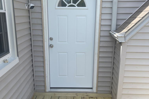 A white door on a house, framed by a welcoming porch, inviting visitors to enter and enjoy the home’s charm.