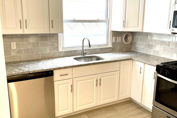 A modern kitchen featuring stainless steel appliances and sleek white cabinets, creating a bright and contemporary atmosphere.