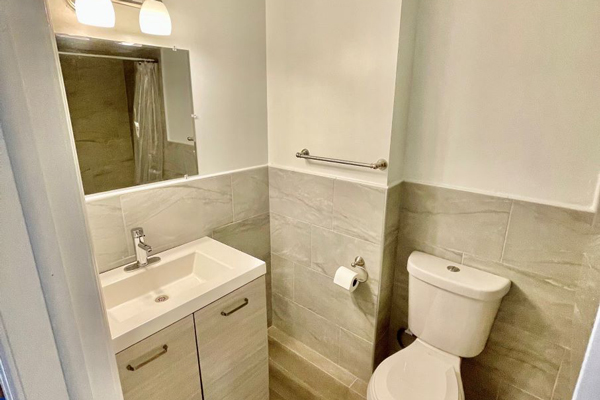 A clean bathroom featuring a toilet, sink, and mirror, showcasing a modern and functional design.