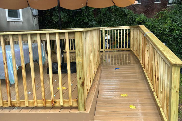 A wooden deck featuring a table and an umbrella, providing a shaded area for relaxation and outdoor dining.