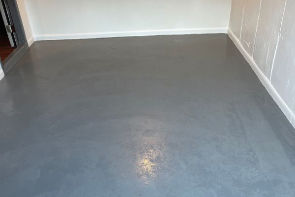 A small room featuring a gray concrete floor, showcasing a minimalist and industrial aesthetic.