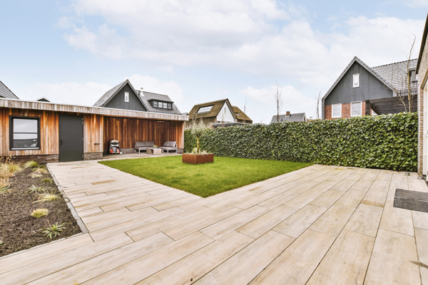 A serene backyard featuring wooden flooring, a lush lawn, and a cozy patio area for relaxation and outdoor gatherings.