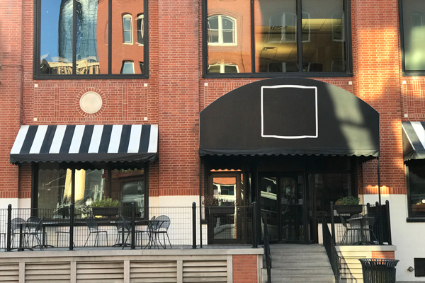 A downtown restaurant showcasing outdoor seating, lively decor, and diners enjoying a variety of dishes in a vibrant environment.